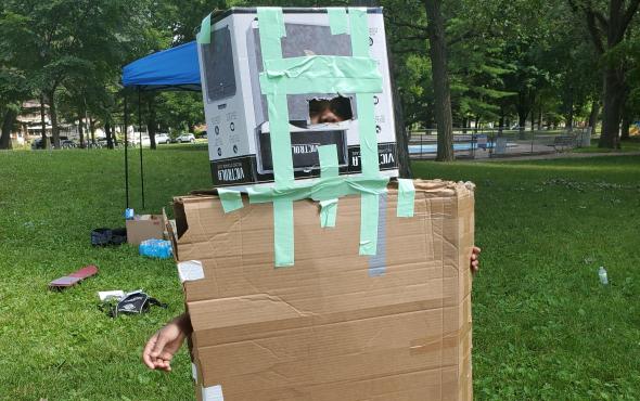 young kid in a cardboard robot costume.