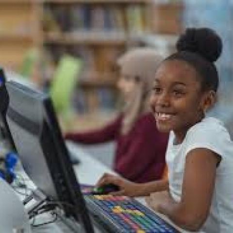 Young woman of color sitting at a computer